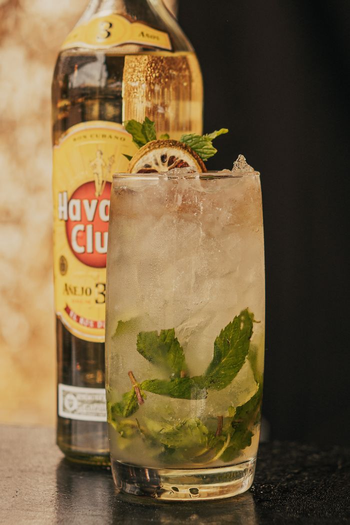services-03 Close-up of a refreshing mojito cocktail with mint and lime in front of a Havana Club bottle.